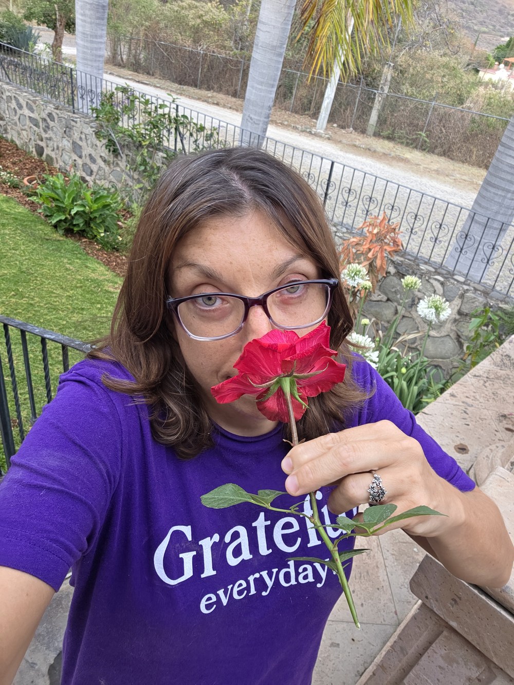 Sherry, founder of Zenfull Heart, smelling a red rose in a garden